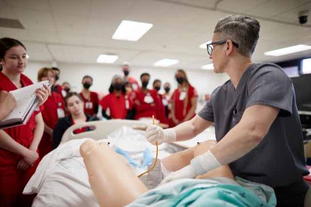 An instructor teaching students on a training mannequin